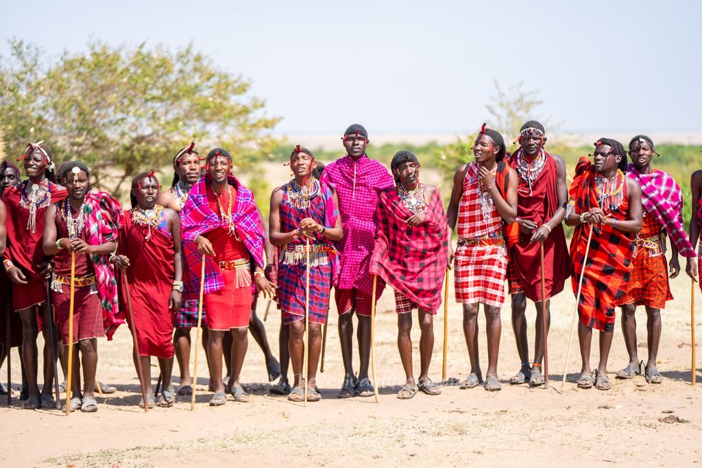 Maasai village visit: men in red shukas singing a welcome song in the Masai Mara