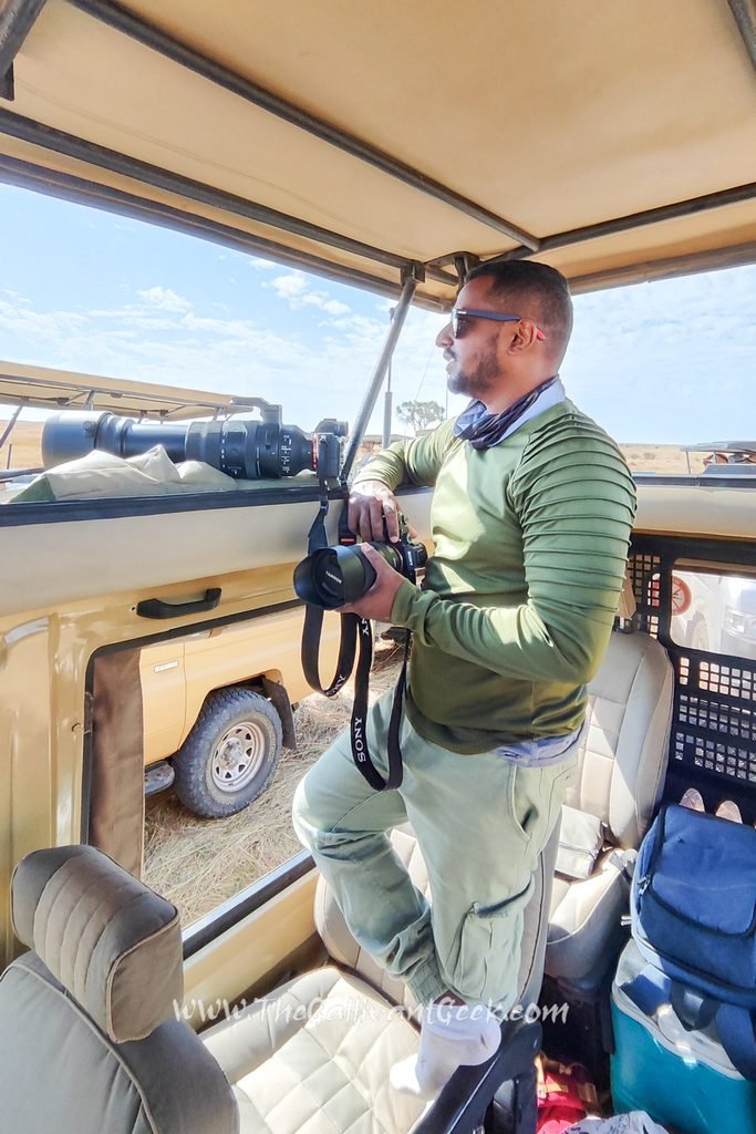 Photographer with two camera bodies standing in an open-roof safari vehicle