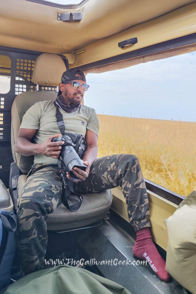 Photographer in neutral-coloured safari clothes with a camera inside a safari vehicle