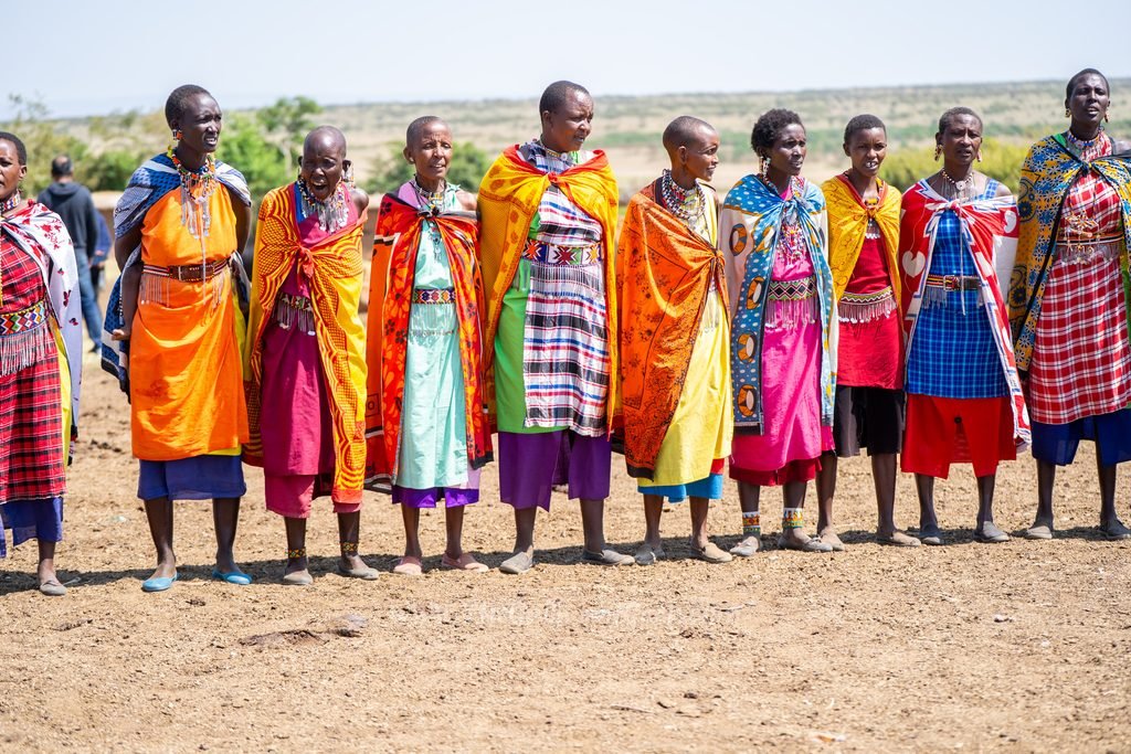 Maasai women in colourful shukas singing a welcome song