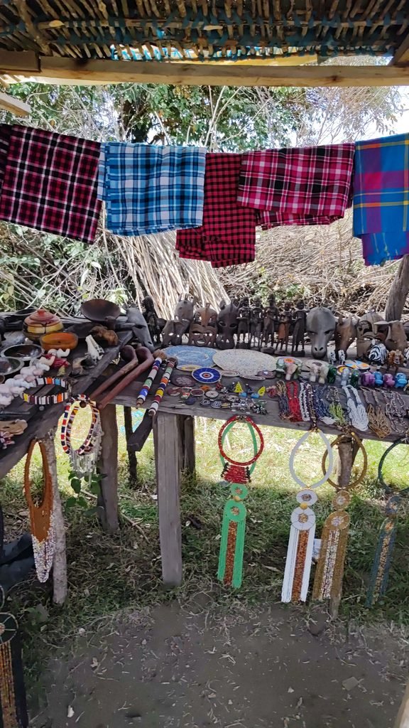 Maasai shukas and handmade souvenirs hanging at a village market in Kenya