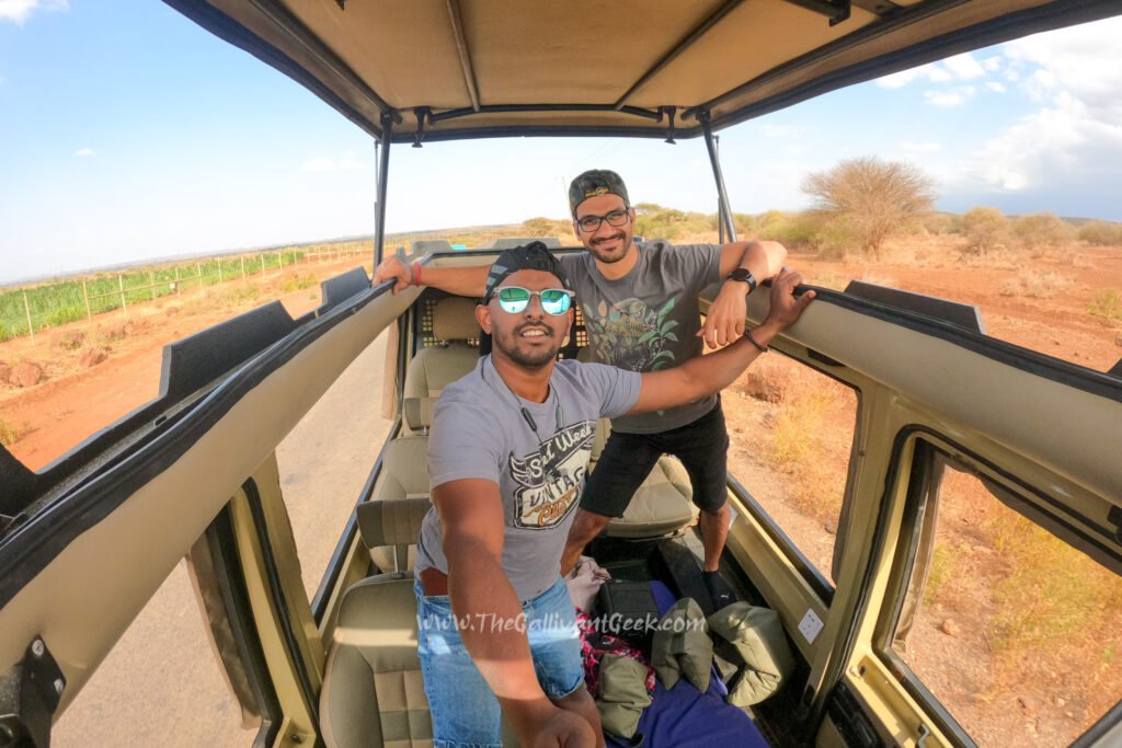 Two friends in T-shirts in an open-roof safari vehicle on a Kenya game drive
