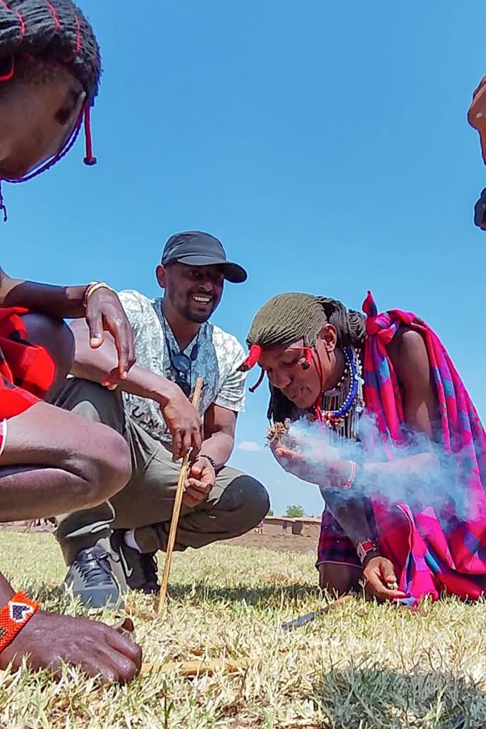 Maasai men making fire by spinning a wooden stick, with smoke rising