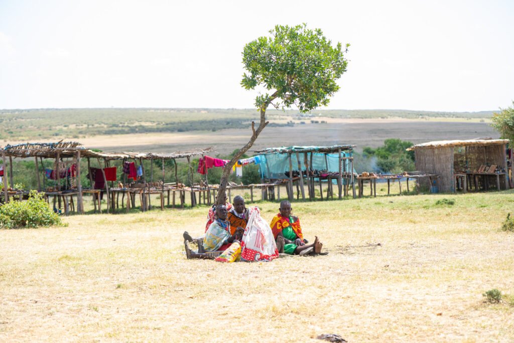 Maasai women resting under an acacia tree in a village in the Masai Mara, Kenya