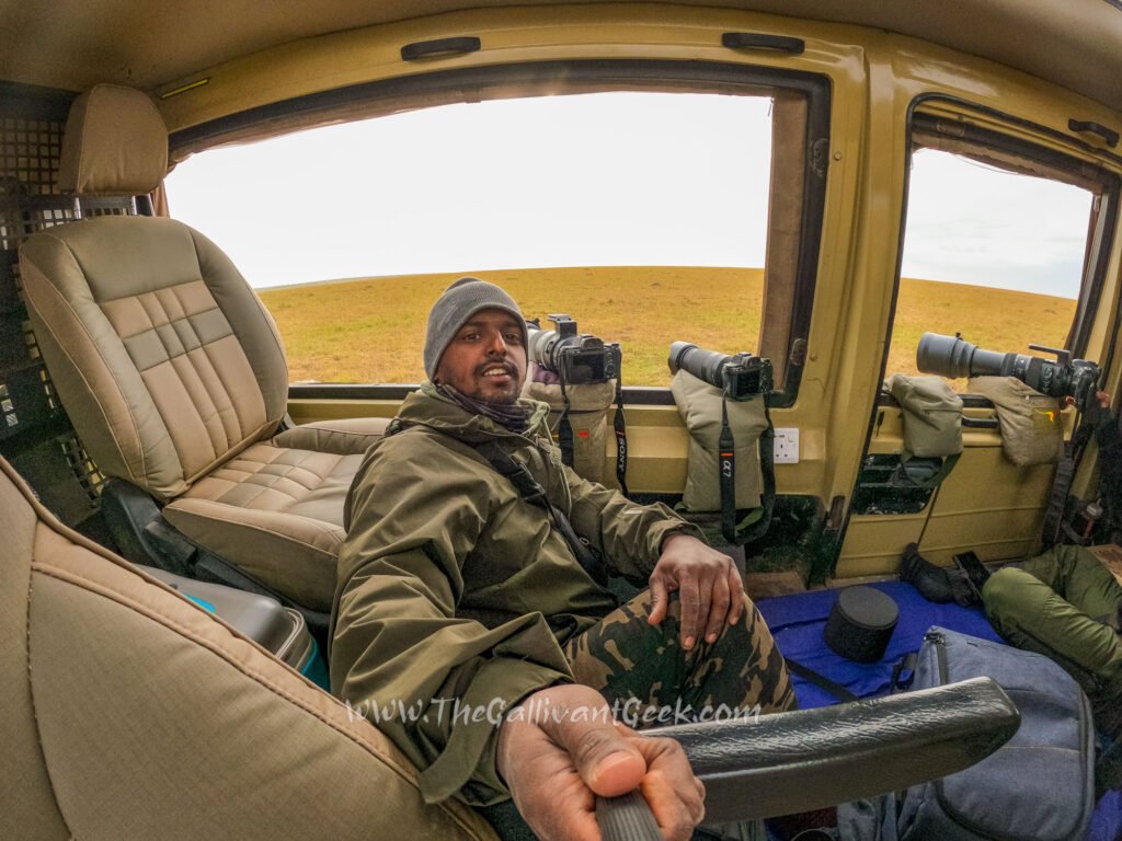 Wildlife photographer with camera gear in an open safari vehicle in the Masai Mara